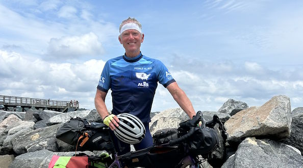 Timm Fenton posing with his bike while cycling across the country to raise money for ALS TDI.